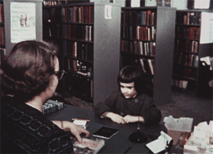 Animated GIF of girl checking out library book from seated librarian, probably 1950s